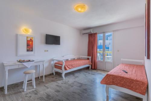 赫索尼索斯Irini Apartments的一间卧室配有一张床、一张书桌和一个窗户。