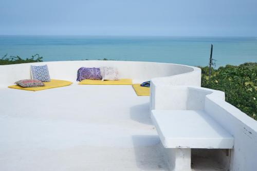 TubaráCasa Caracola的一张白色长凳,上面有两个枕头,上面有大海
