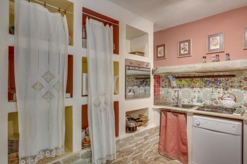 斯波莱托托雷德尔格法尔科公寓的厨房拥有色彩缤纷的墙壁和白色窗帘