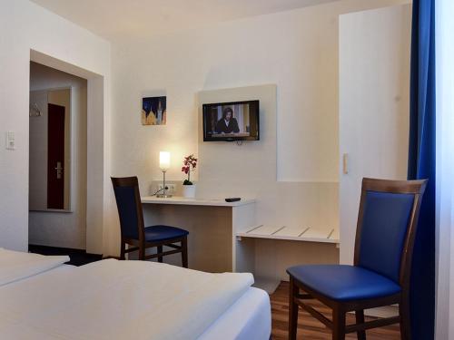 慕尼黑奥林匹亚酒店的酒店客房,配有两张床、一张桌子和两把椅子