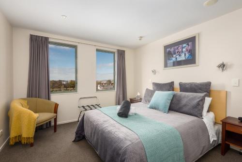基督城Spacious 2 Bedroom Apartment Downtown Christchurch的一间卧室配有一张床、一把椅子和窗户。