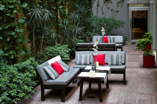 布宜诺斯艾利斯里贝拉苏尔酒店的天井配有沙发和带红色枕头的桌子。