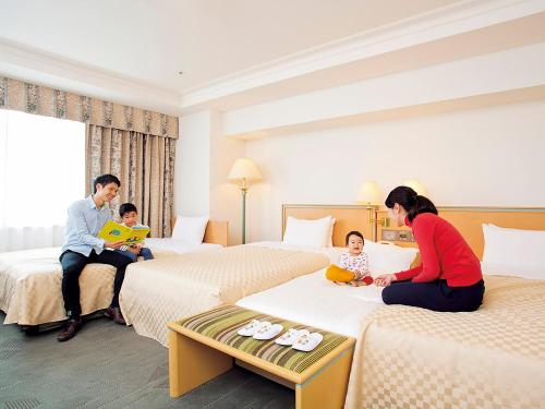 八王子市八王子京王广场酒店的坐在酒店房间床铺上的家庭