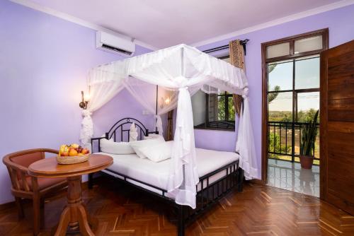 阿鲁沙Mrimba Palm Hotel的一间卧室配有一张天蓬床和一张桌子