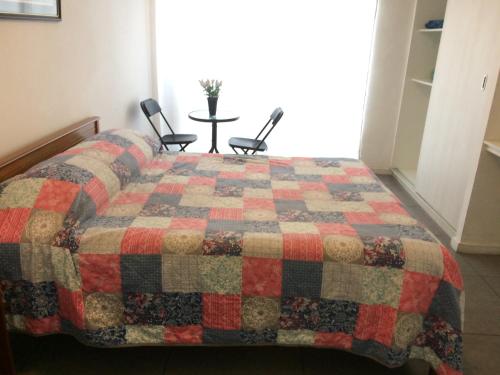 伊基克Hospedaje Amunátegui的一间卧室,床上有被子,床上有两把椅子