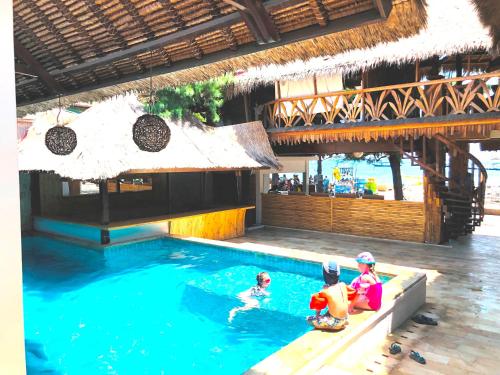 吉利特拉旺安桑巴海滨景观别墅酒店的三个孩子在度假村的游泳池玩耍