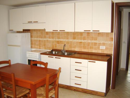奥里斯塔诺Casa Liliana的厨房配有白色橱柜、桌子和水槽。