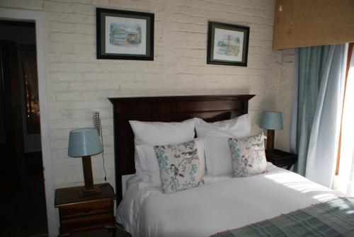 逊邱伦Hampton House Guest House的卧室配有一张床,墙上挂有两张照片