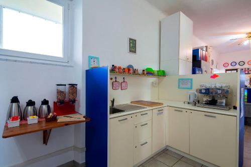 克里日亚Ostello Corniglia的厨房配有白色橱柜和蓝色冰箱。