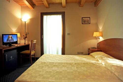 圣焦尔焦迪诺加罗维多利亚酒店的一间卧室配有一张床、一张书桌和一台电视
