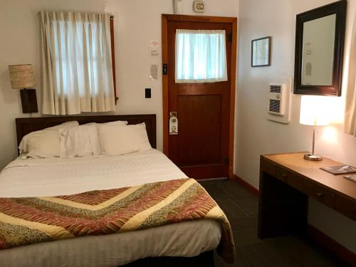 卡斯特Chalet Motel的一间卧室配有一张床和一张带台灯的书桌