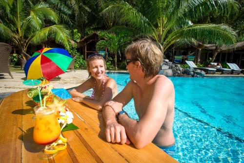 奥法加Seabreeze Resort Samoa – Exclusively for Adults的坐在桌边的男人和一个小女孩