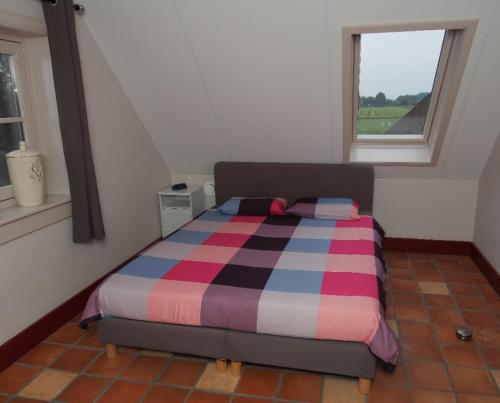 BennekomNeyenGreve的一间卧室配有带条纹棉被的床和窗户
