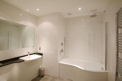圣彼得港巡防舰酒店的白色的浴室设有浴缸和水槽。