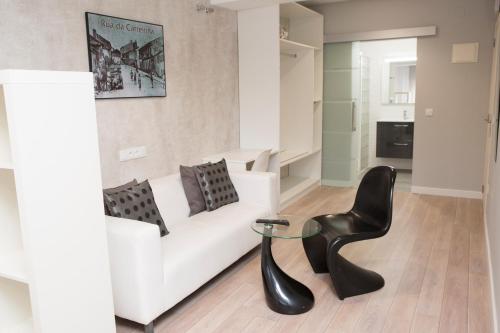 诺雅Hostal Kukia的客厅配有白色沙发和黑椅