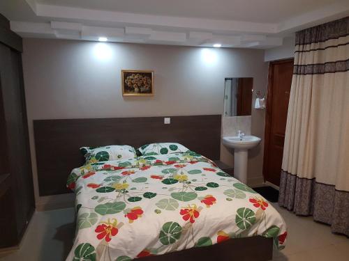 MeruAdala Motel的一间卧室配有一张带花卉棉被和水槽的床