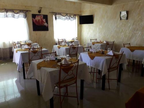 MeruAdala Motel的用餐室配有桌椅和白色桌布