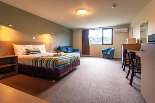 金斯顿Kingston hotel Motel的酒店客房,配有一张床、一张桌子和椅子