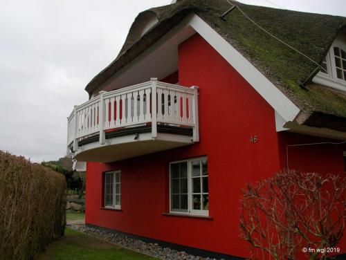 格罗斯齐克Landhaus Uhlenhof 4的红色的房子,上面有白色的阳台