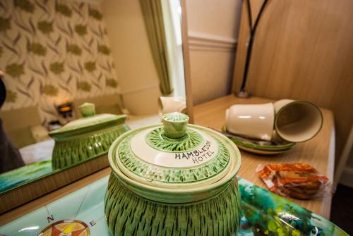 尚克林Hambledon Hotel的绿色花瓶坐在镜子前的桌子上
