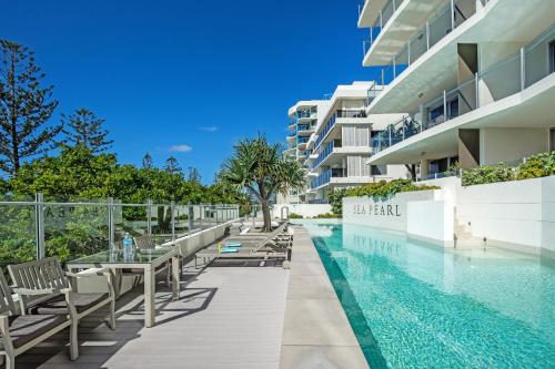 穆卢拉巴Sea Pearl A1 Beach Resort的一座带桌椅的无边泳池位于一座大楼旁