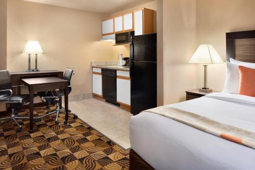 密尔沃基Hawthorn Suites By Wyndham Oak Creek/Milwaukee Airport的酒店客房配有一张床、一张书桌和一间厨房。