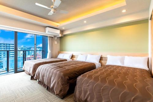 宜野湾市Yenns Marina Inn Mercy的配有窗户的酒店客房内的两张床