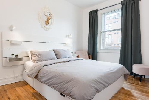 蒙特利尔Apartments Near Montreal Olympic Park的白色的卧室设有床和窗户