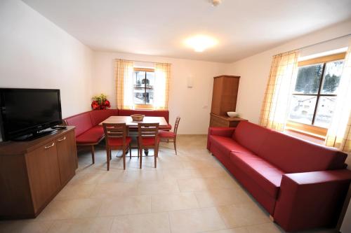 塞尔瓦迪加尔代纳山谷Apartments Restaurant Rusctlea的客厅配有红色的沙发和桌子