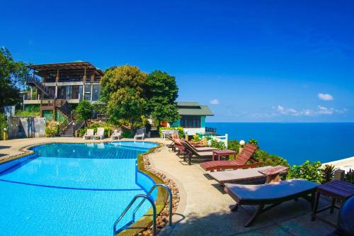 美翰帕岸岛乌托邦度假酒店的毗邻大海的带桌椅的游泳池