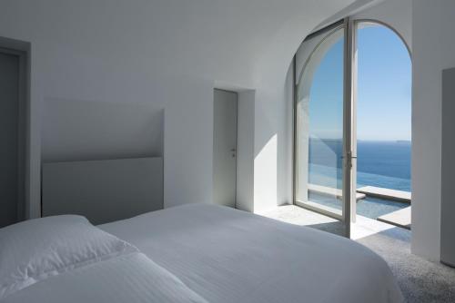 伊亚Echoes Luxury Suites的卧室设有白色的床和大窗户