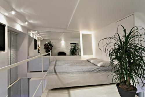 巴黎时尚豪华巴黎市中心复式公寓的一间白色的卧室,配有床和盆栽植物
