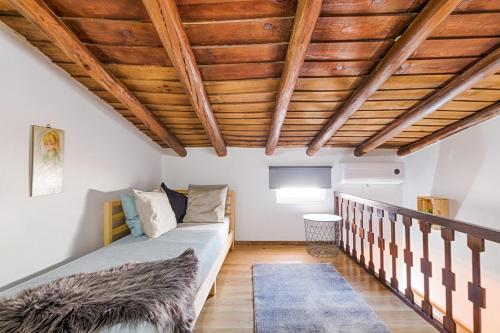 BrinchesCasa dos Moinhos Velhos的一间卧室设有一张床和木制天花板