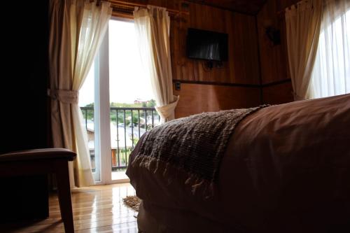 达卡卫Hotel Aliwen的一间卧室设有一张床和一个滑动玻璃门