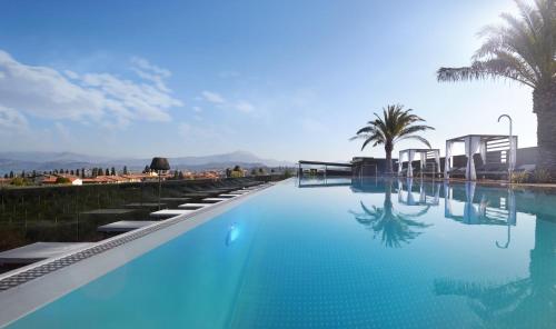拉齐塞Quellenhof Luxury Resort Lazise的一座拥有蓝色海水和棕榈树的游泳池