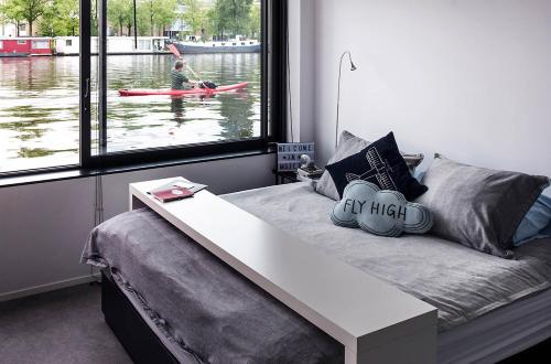 阿姆斯特丹Houseboat Amsterdam - Room with a view的一间房间,配有一张带桌子的床,外面有一名划皮艇的人