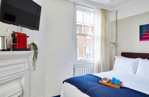 伦敦The Buxton的一间酒店客房,配有一张带托盘的床