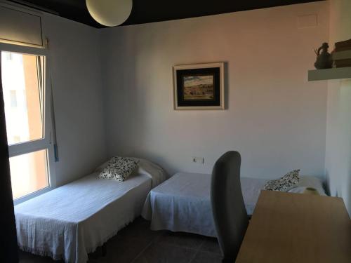 霍斯皮塔勒·德尔英福Piso céntrico 2 habitaciones cerca del mar的客房设有两张床、一张桌子和一扇窗户。