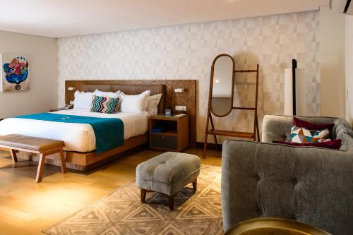 瓜达拉哈拉FCH Hotel Providencia的一间卧室配有一张床、一把椅子和镜子