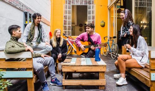 布宜诺斯艾利斯Play Hostel Arcos的一群坐在长椅上演奏音乐的人