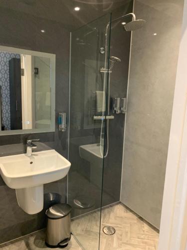 米查姆木麻黄树酒店的一间带水槽和玻璃淋浴的浴室