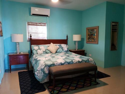 夏洛特阿马利亚Villa Indigo Sunny 1BR Apartment in Private Gated Estate的一间卧室设有蓝色的墙壁、一张床和两盏灯。