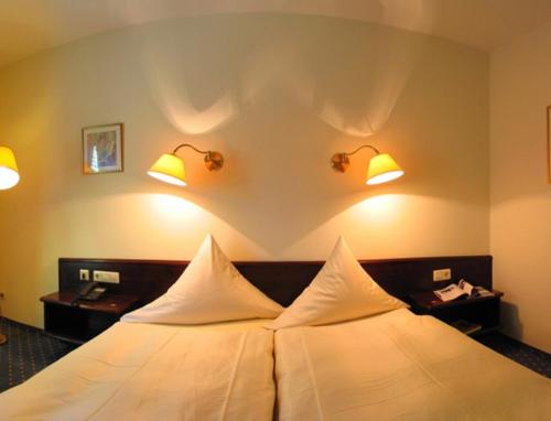 胡根尔舍姆Hotel Waldhaus的酒店客房的墙上设有一张带灯的床铺。