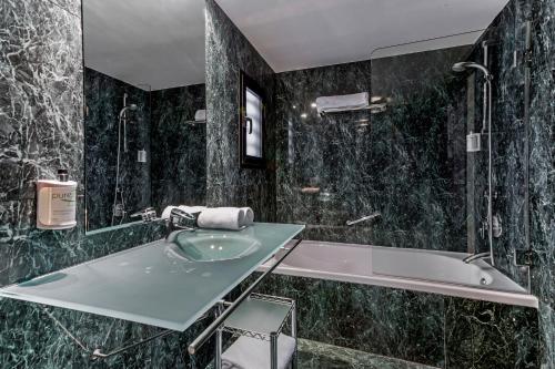 萨拉戈萨B&B HOTEL Zaragoza Los Enlaces Estación的黑色大理石浴室设有水槽和浴缸