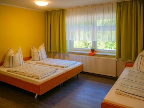BertsdorfGästehaus am Oberlausitzer Dreieck的配有两张床的客房,设有黄色的墙壁和窗户