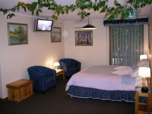 斯特灵Adelaide Hills B&B Accommodation的一间卧室配有一张床和两张蓝色椅子