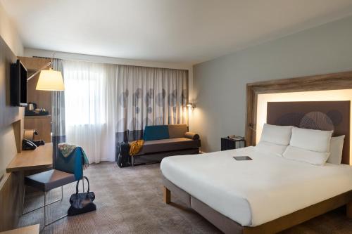 考文垂诺富特考文垂酒店的酒店客房设有一张大床和一张沙发。