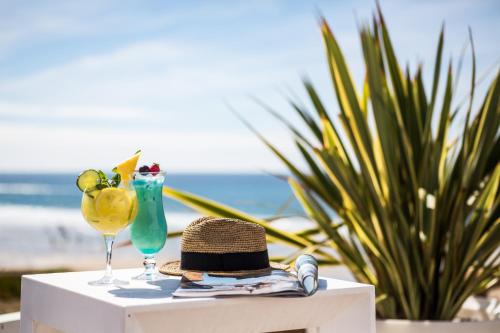 比斯卡罗斯海滩德拉普拉奇乐格兰德酒店的沙滩上桌子上一顶帽子和两杯眼镜