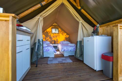 拉宾Kamp Romantik - glamping的带2张床和冰箱的帐篷客房