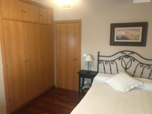 格拉纳达Habitación doble independiente con baño compartido的卧室配有白色的床和木制橱柜。